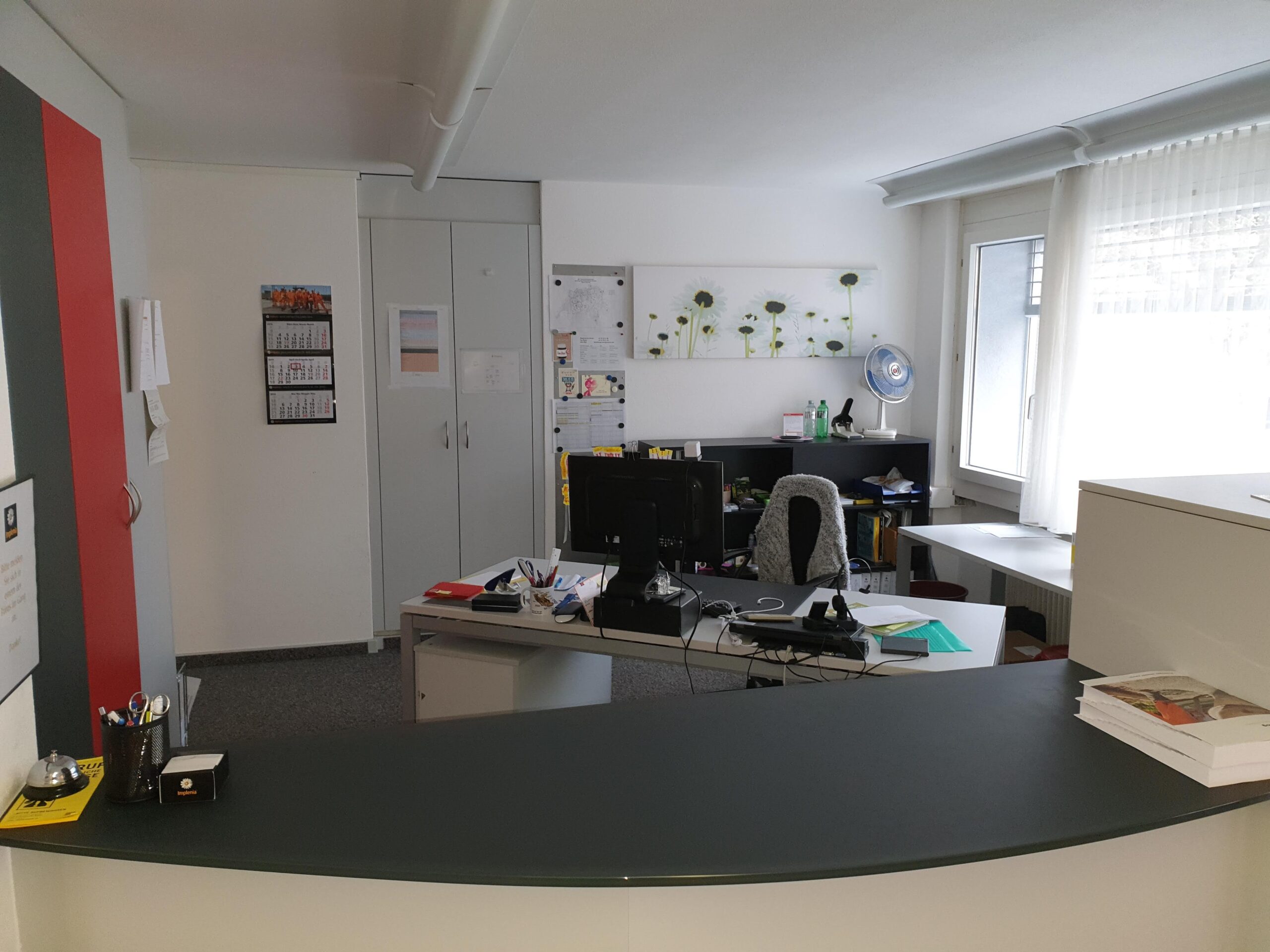 offenes Büro mit einem Bürotisch und Schränken,. Es sind diverse Gegenstände ersichtlich .